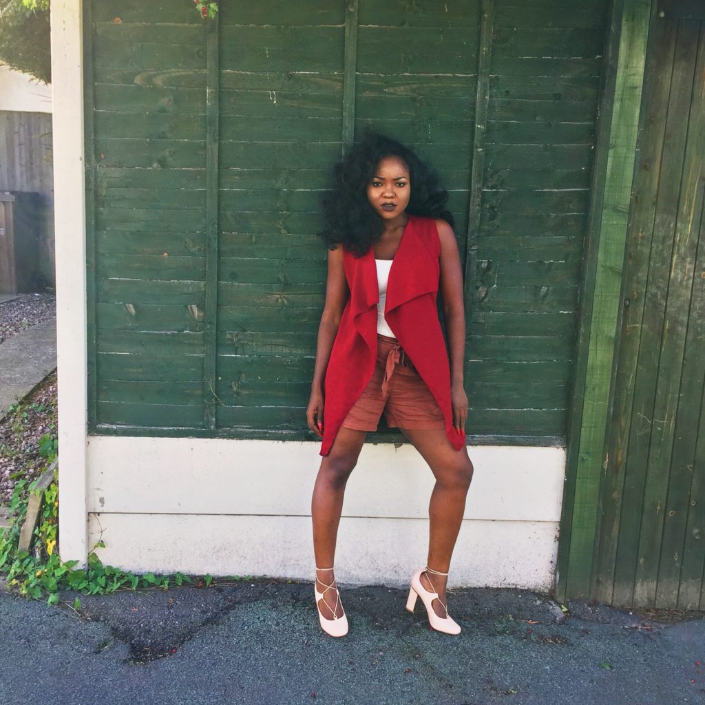 Lady resting on a wooden door wearing burgundy and nude ensemble 